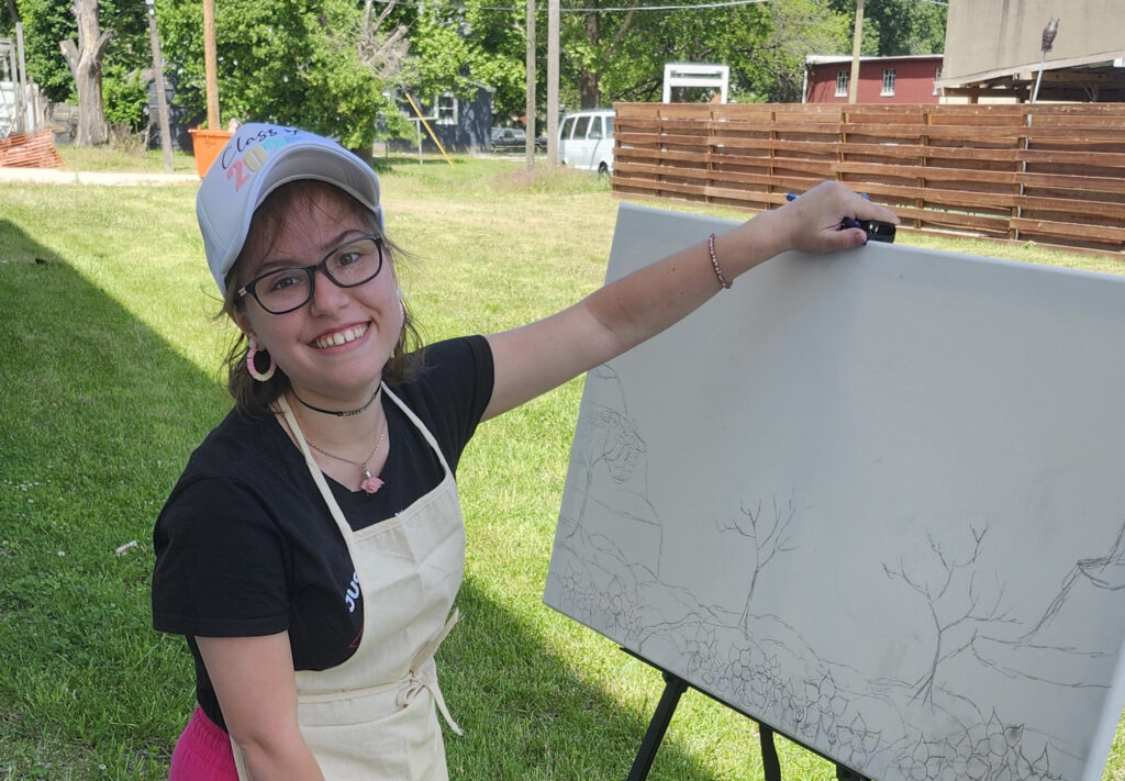 Picture of Phoebe Trites in front of an easel outside